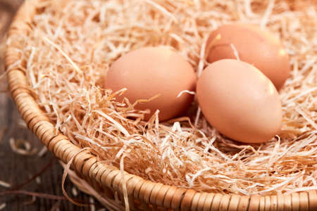 Macro of three raw eggs in an easter nest with straw in a basket.の写真素材
