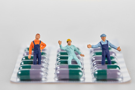 Miniature people placed on blister package with medical pills
