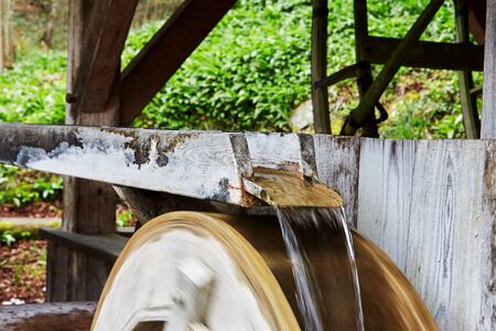 Water running over the turning wheel of a millの写真素材