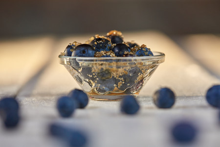 Blueberries and brown sugar in a glass bowl on a white tableの写真素材