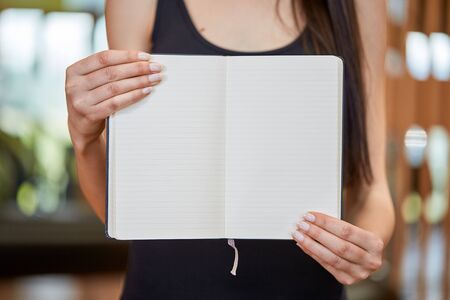 Young caucasian woman holding and showing book with white pagesの写真素材