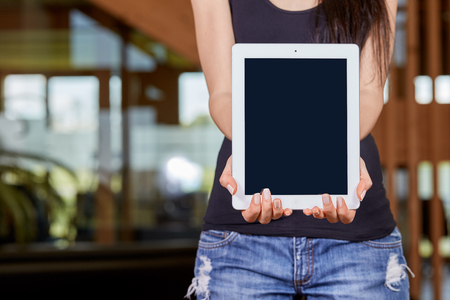 Young caucasian woman holding tablet in front of office hallwayの写真素材