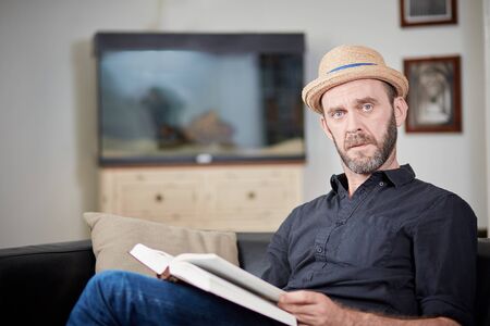 Caucasian hipster with book looking seriously to cameraの写真素材