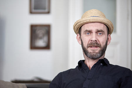 Friendly man with hat and beard portrait at homeの写真素材