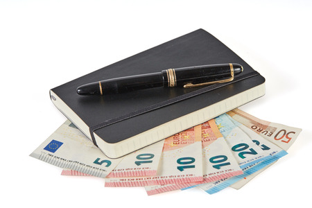 Earning money with writing symbolized with pen and notebook on euro money banknotesの写真素材