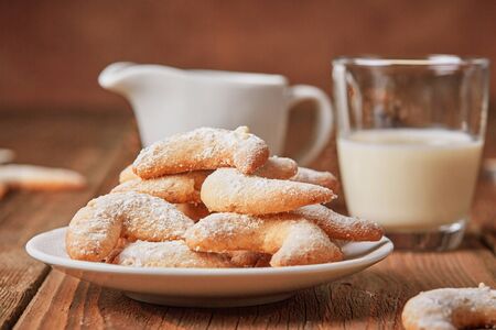Vanilla horse shoe cookies on a plate with a glass of milk on wooden tableの写真素材