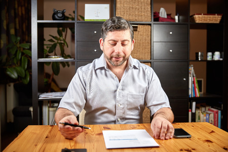 Man sitting in at a table with document at homeの写真素材