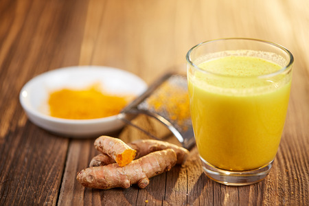 Turmeric curcuma orange drink with roots on wooden tableの写真素材