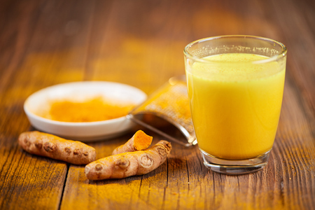 Trumeric orange golden milk with root and powder o a wooden tableの写真素材