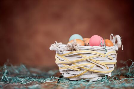 Easter basket and grass onwooden table in front of brown wallの写真素材