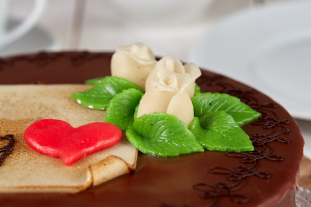 Delicious chocolate cake with marzipan rose on white table with white chinaの写真素材