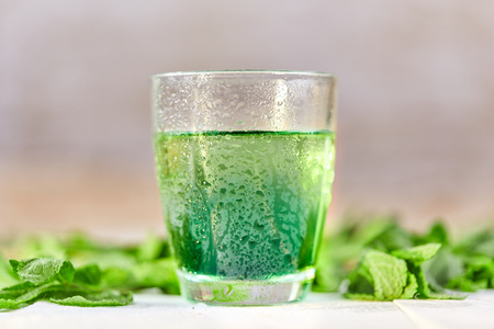 Green mint chlorophyll drink in glass with water drops on white tableの写真素材