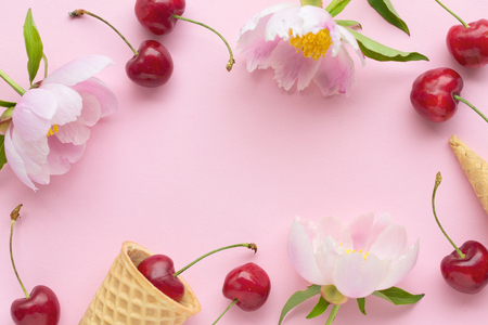 Spring or summer mood concept. Flatlay of cerry, sweet cones and peonies over pastel pink background. Top view with space for your textの写真素材