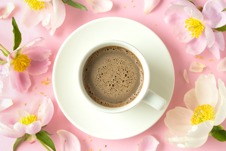 Spring or summer morning concept. Flat-lay of coffee and flowers over light pink background, top view with space for your textの写真素材