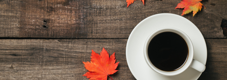 Autumn leaves and a cup of coffee with plaid on old vintage wooden background. Top view with space...