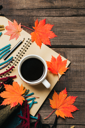 Autumn leaves and a cup of coffee with plaid on old vintage wooden background.の写真素材