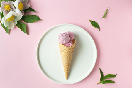 Spring or summer mood concept. Flat-lay of waffle sweet cone with berryy over pastel light pink background, top view.の写真素材