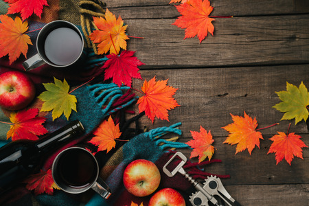 Autumn leaves, two cups of wine, red apples with plaid on old vintage wooden background.の写真素材