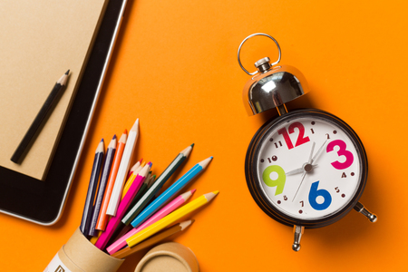 Collage with round clock, pencil and notebook on orange background, time concept.の写真素材
