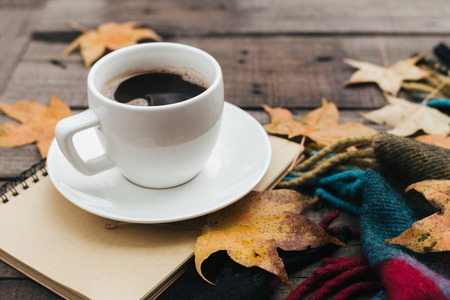 Cozy autumn composition with plaid leaves and a cup of coffee on old vintage wooden background. Copy space.の写真素材