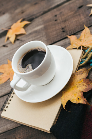 Cozy autumn composition with plaid leaves and a cup of coffee on old vintage wooden background. Copy space.の写真素材