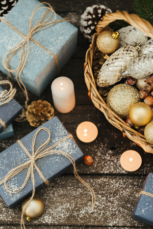 Festive Gifts with Boxes, Candle, Snow, Coniferous, Basket, Cinnamon, Pine Cones, Nuts on Wooden Background.の写真素材