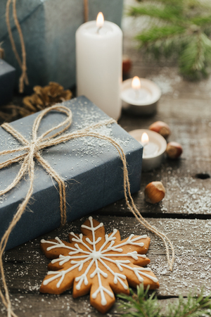 Festive Gifts with Boxes, Candle, Snow, Coniferous, Basket, Cinnamon, Pine Cones, Nuts on Wooden Background.の写真素材