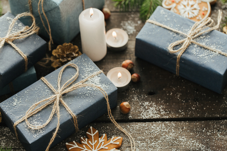 Festive Gifts with Boxes, Candle, Snow, Coniferous, Basket, Cinnamon, Pine Cones, Nuts on Wooden Background. With space for your textの写真素材