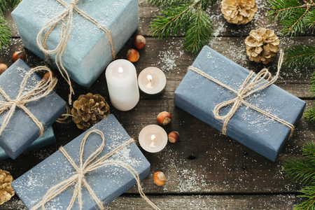 Festive Gifts with Boxes, Candle, Snow, Coniferous, Basket, Cinnamon, Pine Cones, Nuts on Wooden Background. With space for your textの写真素材