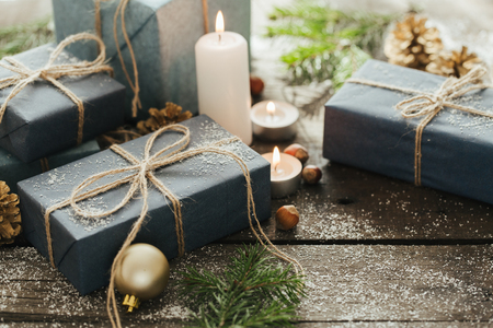 Festive Gifts with Boxes, Candle, Snow, Coniferous, Basket, Cinnamon, Pine Cones, Nuts on Wooden Background. With space for your textの写真素材