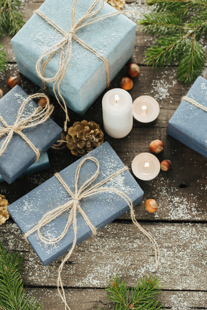 Festive Gifts with Boxes, Candle, Snow, Coniferous, Basket, Cinnamon, Pine Cones, Nuts on Wooden Background. With space for your textの写真素材