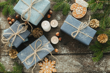 Festive Gifts with Boxes, Candle, Snow, Coniferous, Basket, Cinnamon, Pine Cones, Nuts on Wooden Background. With space for your textの写真素材
