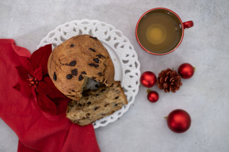 Top view of chocolate-chips Panettone and cup of tea on white tableの写真素材