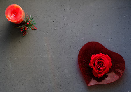 Red rose on heart-shaped plate, on grey backgroundの写真素材