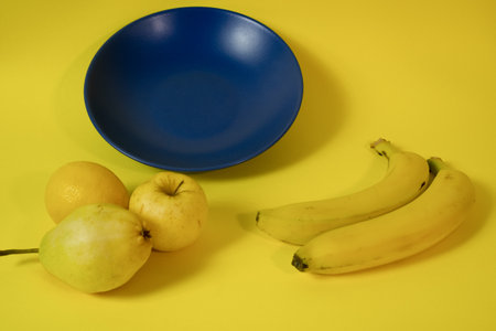 Blue plate on a yellow background with fruits around