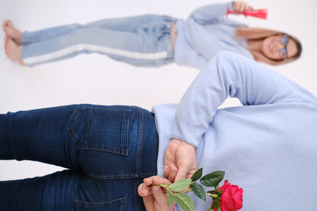Young attractive man holding a rose behind his back to surprise his lover.の写真素材