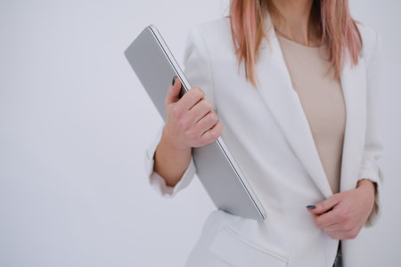 Business woman in white jacket holding a laptop. White background. Copy spaceの写真素材