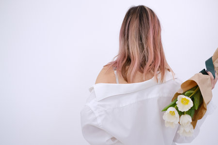 Woman in white shirt holding a bouquet of white tulips on a white background.の写真素材