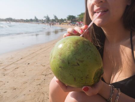 Woman Drinking Coconut at Tropical Beach in Brazilの写真素材