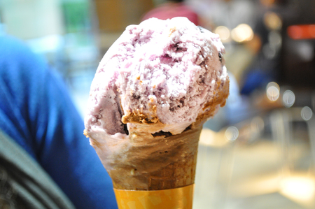 Close up of woman hand holding fresh waffle cone with Strawberry ice cream