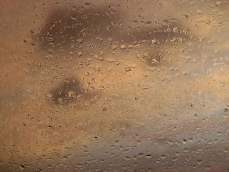 Rain drops over the window at sunsetの写真素材