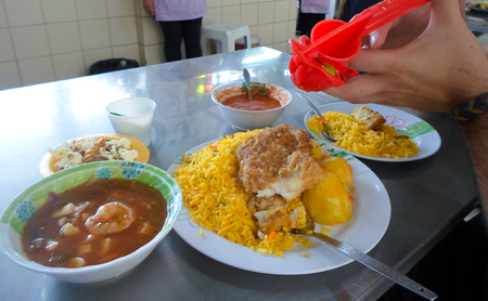 QUITO, ECUADOR - MARCH 18, 2016:  Pouring lemon juice on a Corvina with rice dish in a typical market at the historic center of Quito, Ecuadorのeditorial素材
