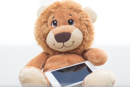 Stuffed lion on white background with cellphoneの写真素材