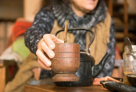 Woman offering yerba mate drink at homeの写真素材