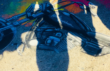 Buenos Aires, Argentina - December 12, 2017: An artist drawing a motorbike in the asphalt is seen...