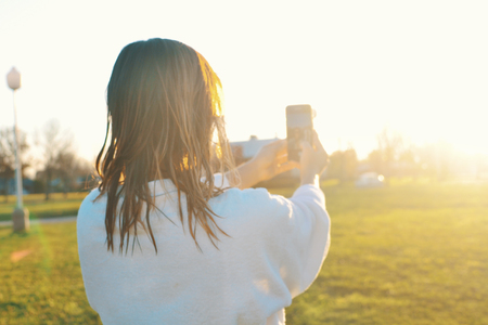 Woman wearing bathrobe taking a selfie photo outdoors at sunsetの写真素材