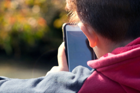 Pre Teen using using smartphone outdoorsの写真素材