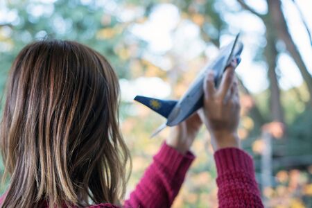 Back view of Woman holding Airplane Tin Toy imagining Travel Outdoorsの写真素材