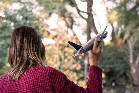 Back view of Woman holding Airplane Tin Toy imagining Travel Outdoors
