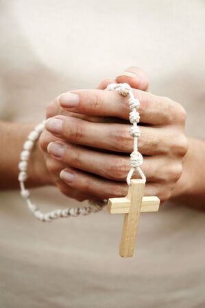 Hands of adult woman praying with a rosaryの写真素材